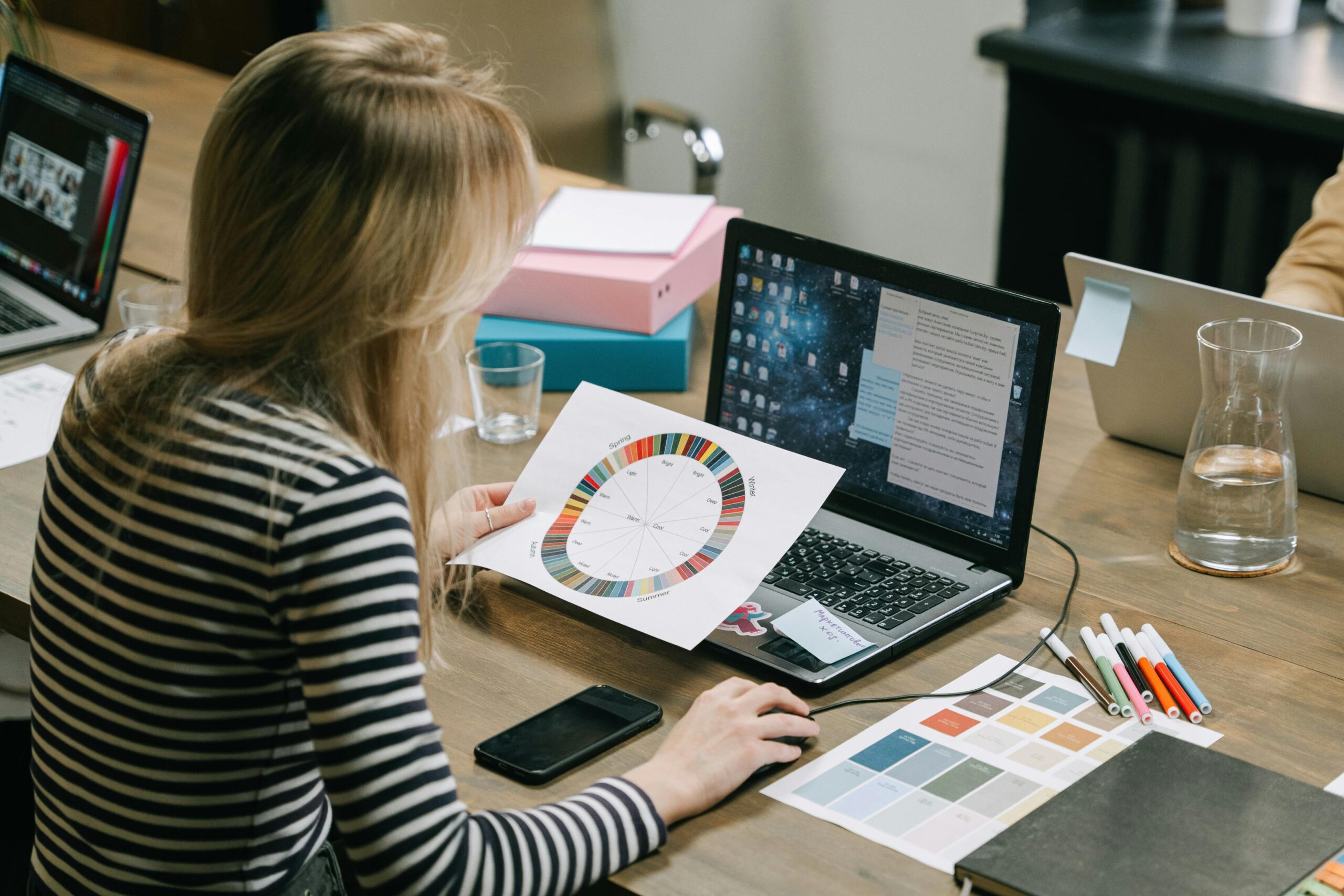 A woman studying a color wheel on a laptop during a work session in a modern office.